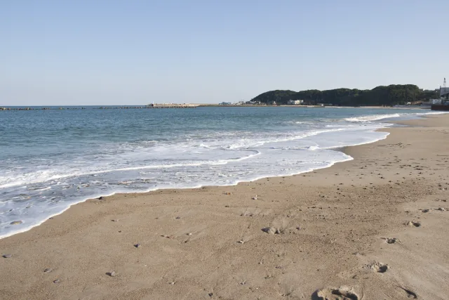 阿字ヶ浦の砂浜に沿って弧を描く波打ち際と青い海