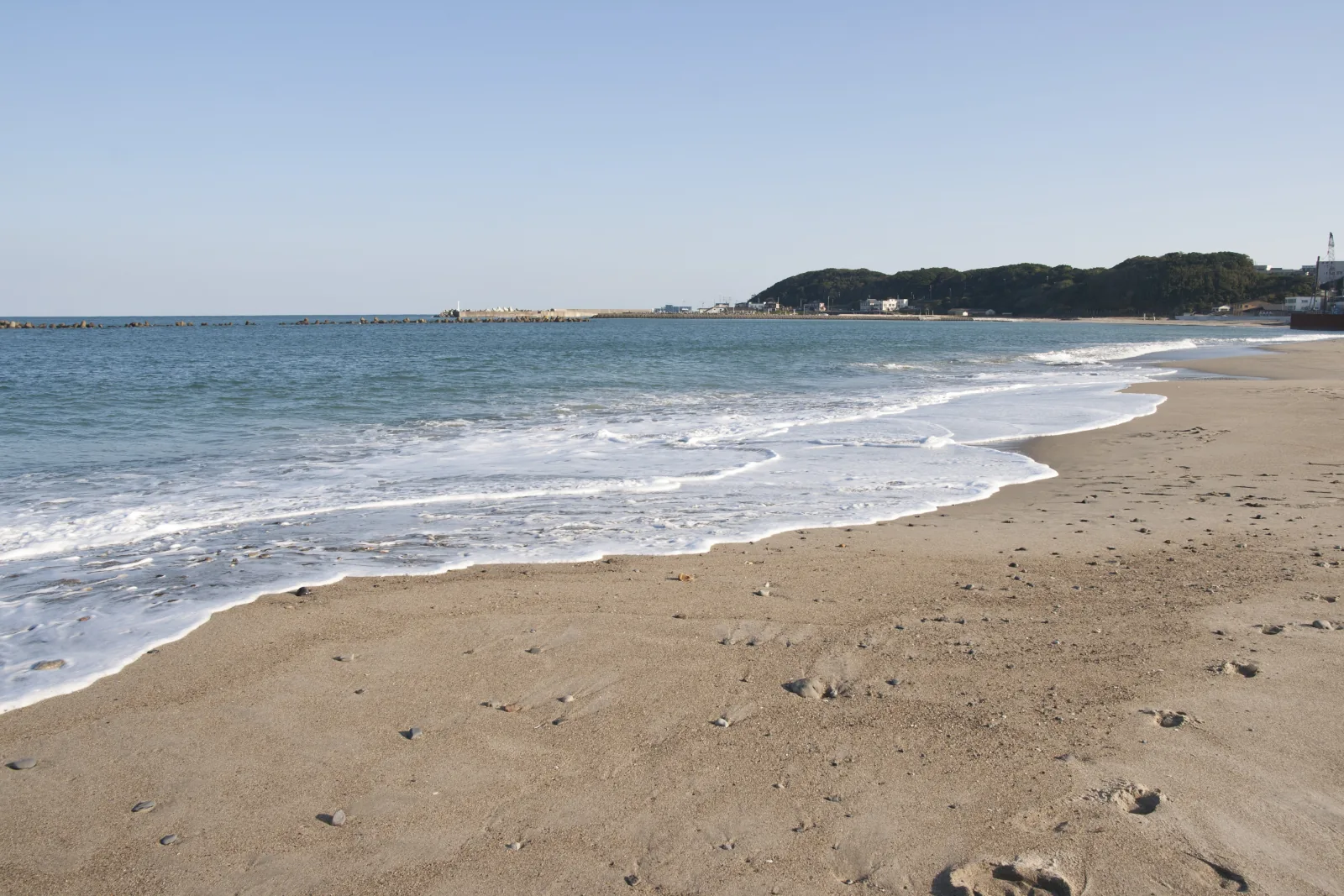阿字ヶ浦の砂浜に沿って弧を描く波打ち際と青い海